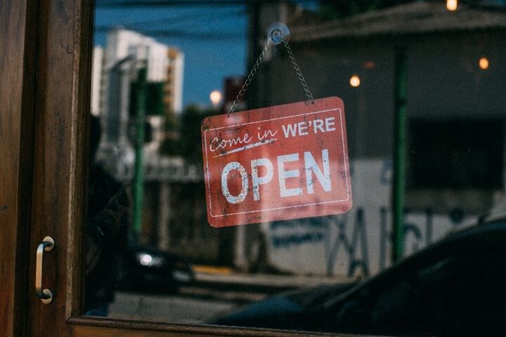 a window with a red sign that says Come In We're Open
