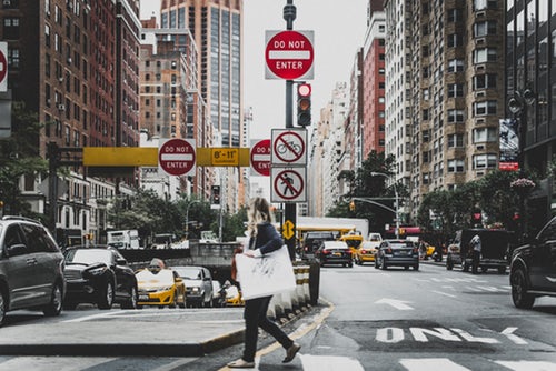 A woman crossing a road with cars.