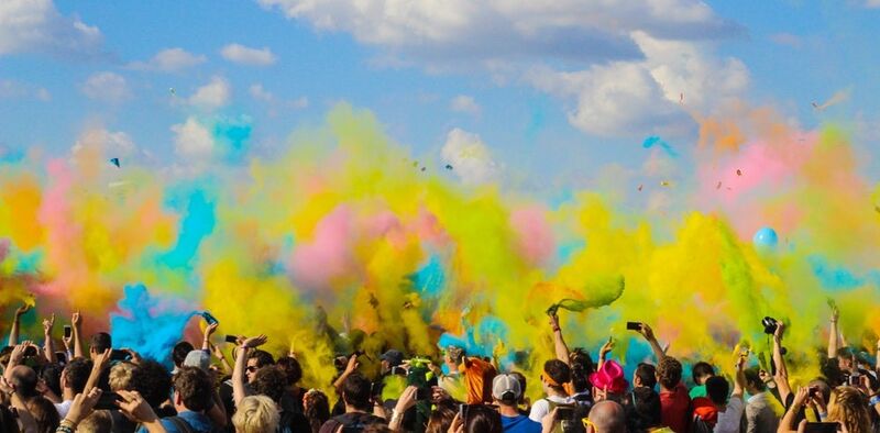 Crowd of people under a blue sky with yellow, blue, and pink colors above them