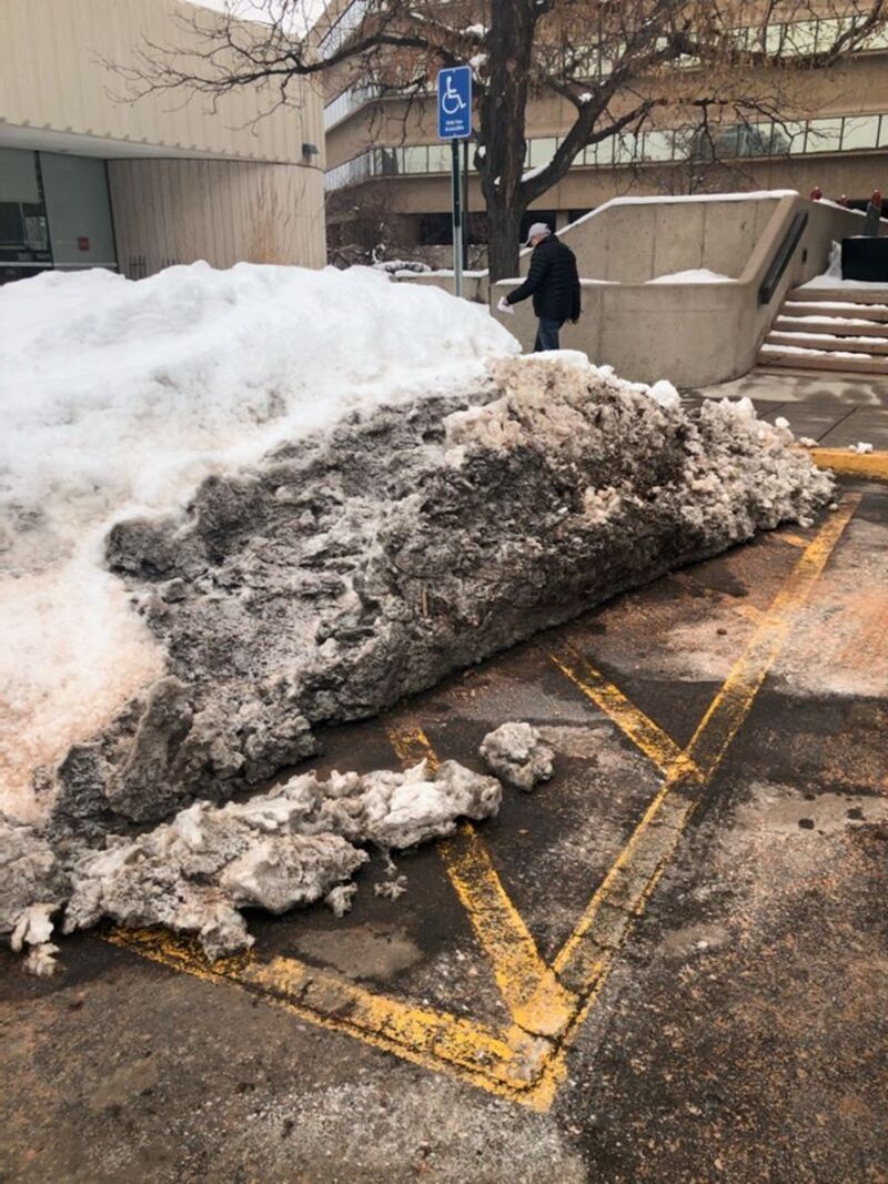Huge pile of snow in an accessible parking space and access isle.