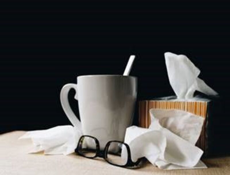 White ceramic mug, tissues, and glasses on a table.