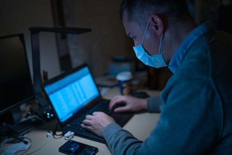 Man with a surgical mask on using laptop.