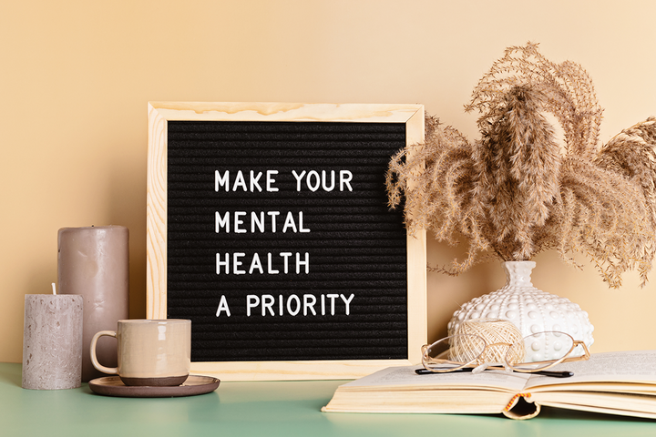 a black letterboard, on a desk, with the words "Make Your Mental Health a Priority" in white.