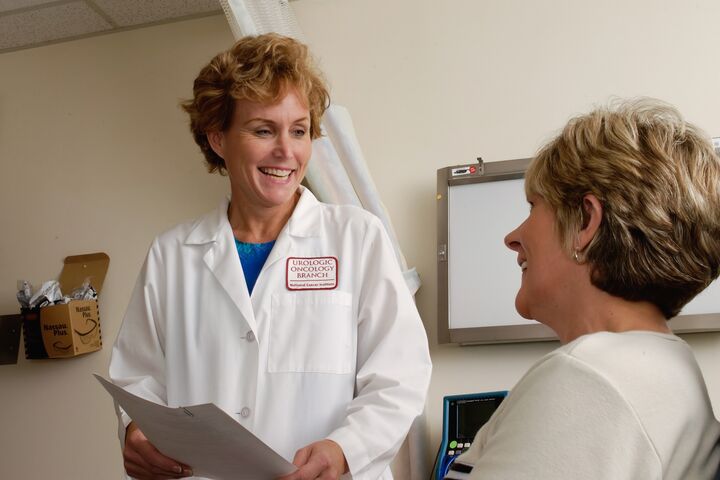 a middle-aged white woman with short blonde hair who is a doctor is smiling at a patient who is also a middle-aged white woman with short blonde hair