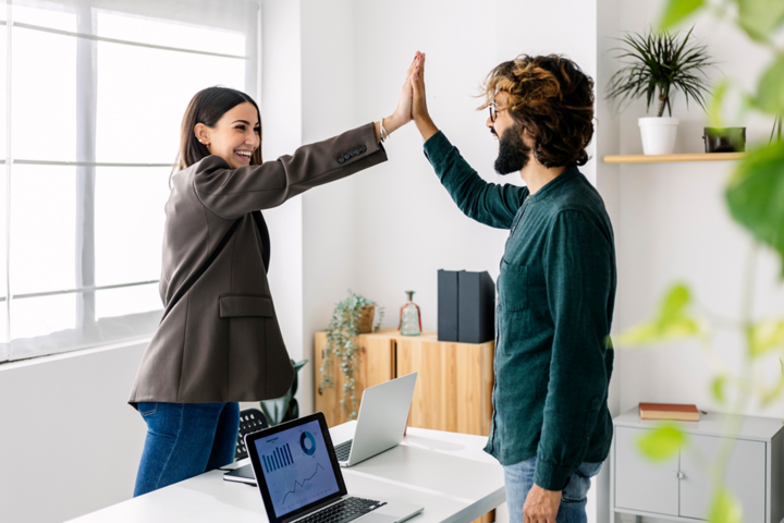 Two work colleagues high five one another.