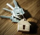 A set of keys on a keychain with a small wooden cutout of a house.